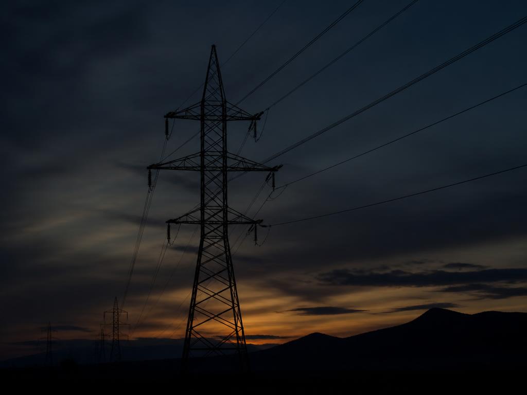 High-voltage transmission pylon silhouetted at dusk